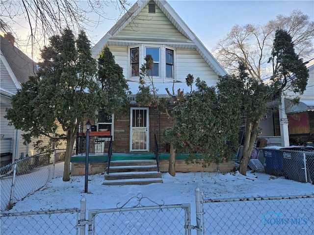 view of front facade with brick siding, a fenced front yard, and a gate