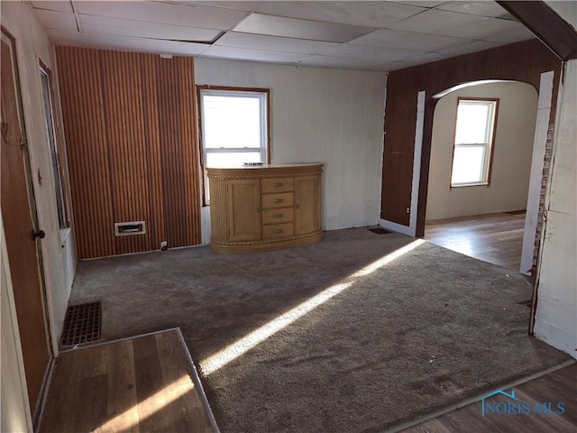 unfurnished room with arched walkways, carpet floors, a drop ceiling, and visible vents