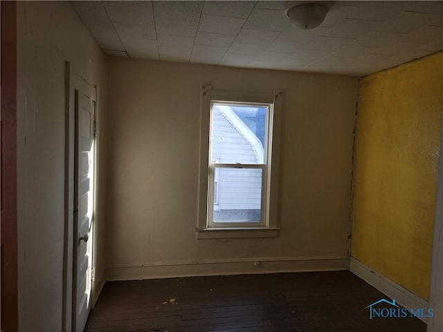 spare room with dark wood-type flooring and baseboards