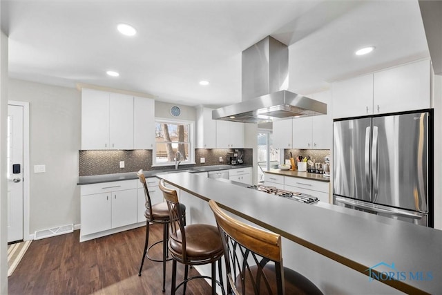 kitchen with visible vents, dark countertops, appliances with stainless steel finishes, island exhaust hood, and white cabinetry