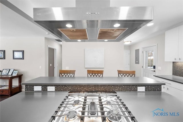 kitchen with recessed lighting, exhaust hood, white cabinetry, tasteful backsplash, and dark countertops