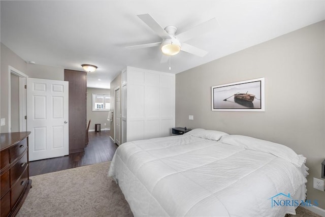 bedroom featuring a ceiling fan, dark wood finished floors, and a closet