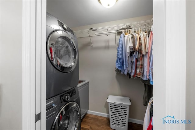 laundry area featuring laundry area, dark wood-style flooring, stacked washer and clothes dryer, and baseboards