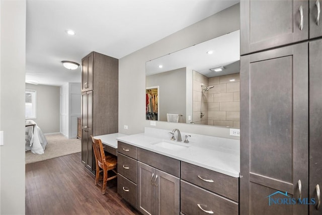 ensuite bathroom with connected bathroom, wood finished floors, vanity, a shower stall, and a walk in closet