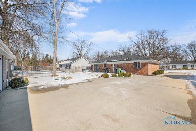 view of front of house featuring a residential view, fence, and brick siding