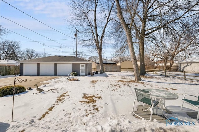 yard covered in snow with a garage, fence, and an outbuilding