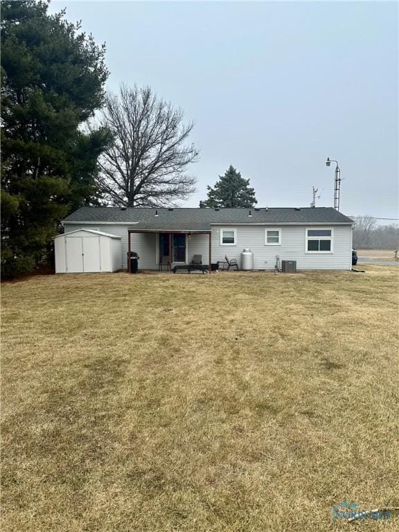 rear view of property with an outdoor structure, cooling unit, a lawn, and a storage shed