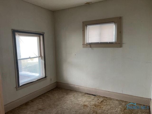 carpeted empty room with visible vents and baseboards