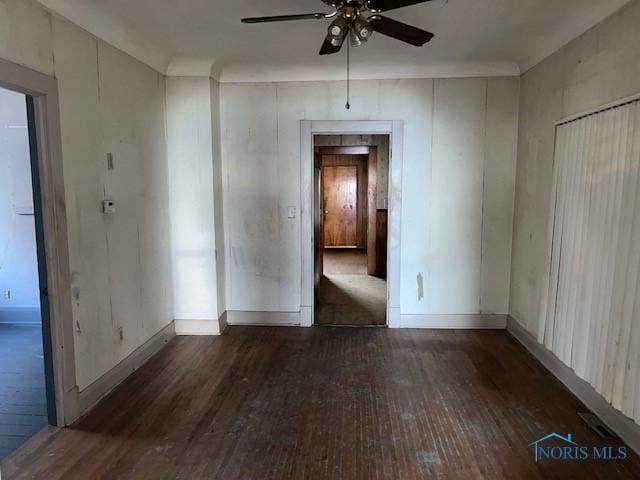 empty room featuring dark wood-style floors, baseboards, and a ceiling fan