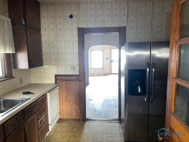 kitchen featuring stainless steel fridge, dishwasher, a sink, and wallpapered walls