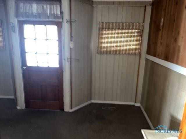 doorway to outside featuring plenty of natural light and wooden walls