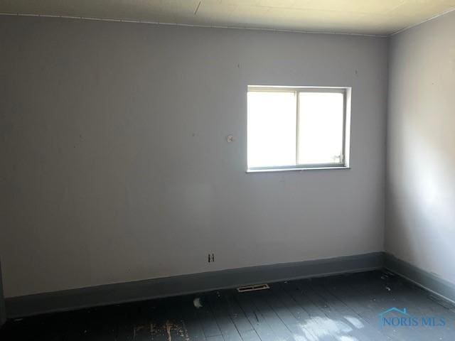 empty room featuring wood-type flooring and baseboards