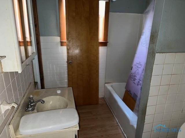 full bathroom with a sink, shower / tub combo, tile walls, and wood finished floors