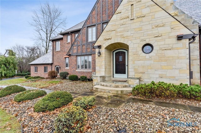 tudor home with brick siding and a shingled roof