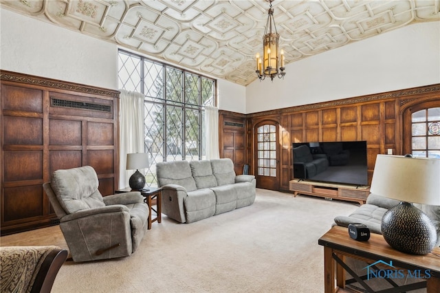 living area featuring light carpet, a high ceiling, an ornate ceiling, and an inviting chandelier