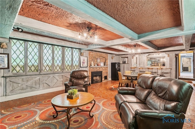 living area with beamed ceiling, a brick fireplace, and coffered ceiling