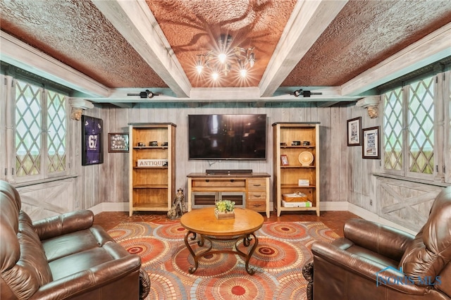 living area with a chandelier, beamed ceiling, wooden walls, and baseboards