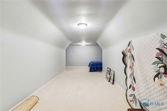 bedroom with baseboards, vaulted ceiling, and light colored carpet