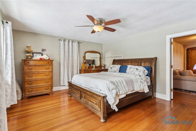 bedroom with wood finished floors, a ceiling fan, and baseboards