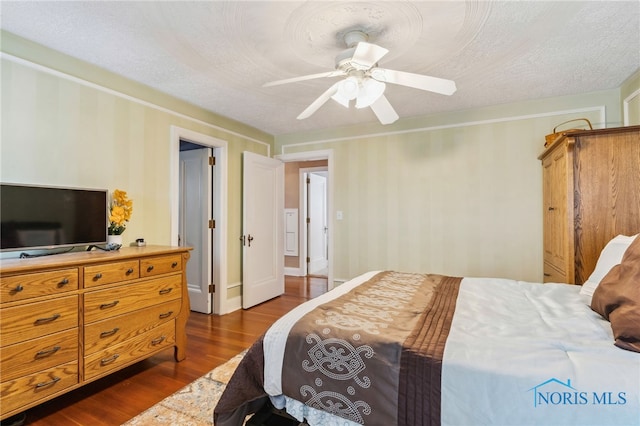 bedroom featuring ceiling fan, dark wood finished floors, and a textured ceiling