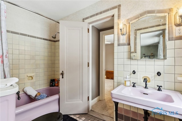 bathroom featuring tile walls, decorative backsplash, toilet, shower / bath combo, and a sink