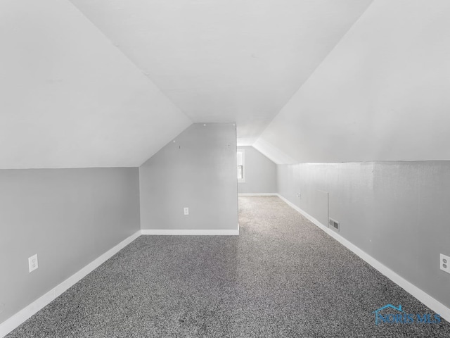 additional living space featuring lofted ceiling, baseboards, visible vents, and carpet flooring