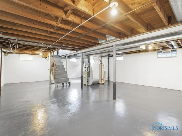 basement featuring water heater, stairway, and heating unit