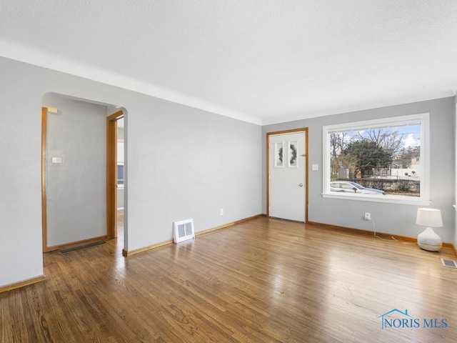 unfurnished living room with visible vents, baseboards, and wood finished floors