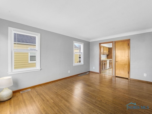 empty room featuring visible vents, baseboards, and wood finished floors