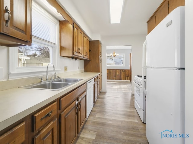 kitchen featuring white appliances, light countertops, a sink, and brown cabinetry