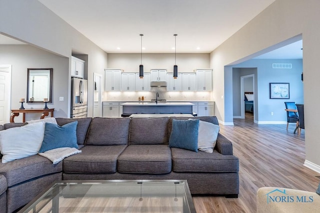 living room with light wood finished floors, visible vents, and baseboards