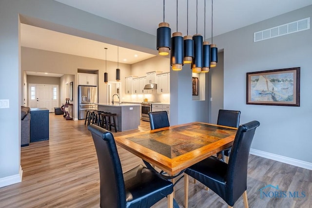 dining room with recessed lighting, visible vents, light wood-style flooring, and baseboards