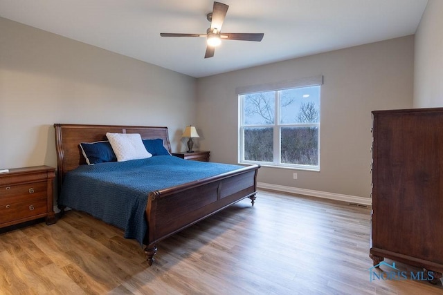 bedroom with light wood-style floors, visible vents, baseboards, and a ceiling fan