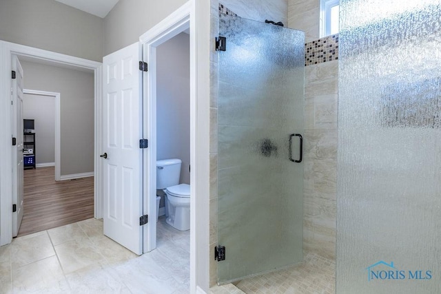 full bathroom featuring baseboards, a stall shower, toilet, and tile patterned floors