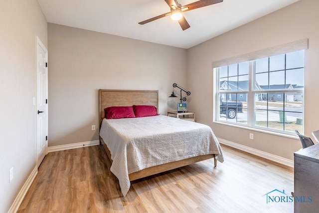 bedroom with ceiling fan, wood finished floors, and baseboards