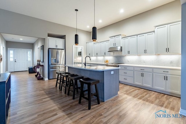 kitchen featuring white cabinets, appliances with stainless steel finishes, light countertops, pendant lighting, and a sink