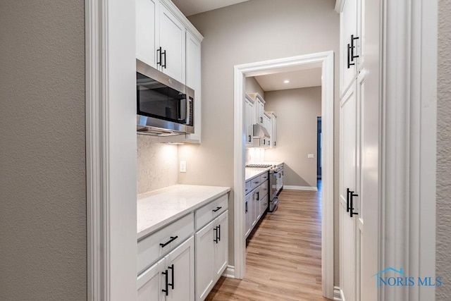 kitchen featuring appliances with stainless steel finishes, white cabinets, and light stone counters