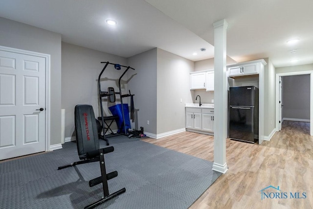 exercise area with recessed lighting, light wood-type flooring, a sink, and baseboards