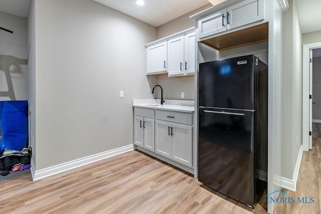 kitchen featuring freestanding refrigerator, light countertops, light wood-style flooring, and white cabinetry