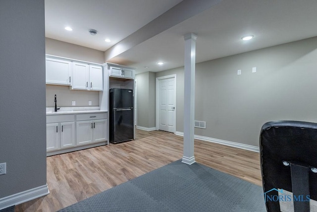 kitchen with light countertops, freestanding refrigerator, white cabinets, and light wood-style floors