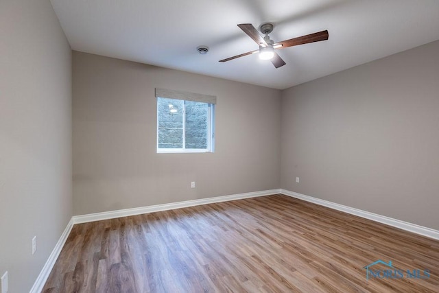 spare room featuring light wood-style floors, ceiling fan, and baseboards