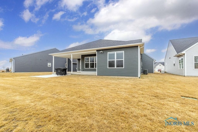 rear view of house featuring a yard, roof with shingles, central AC unit, and a patio