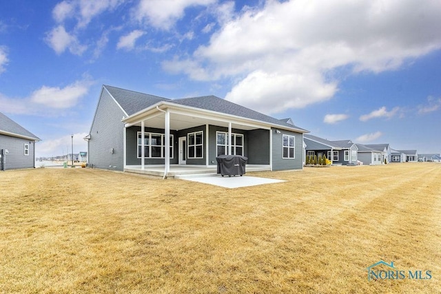 back of property with a patio area and a yard