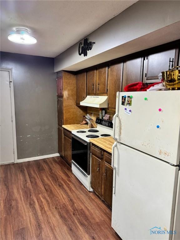 kitchen featuring dark wood finished floors, light countertops, white appliances, under cabinet range hood, and baseboards