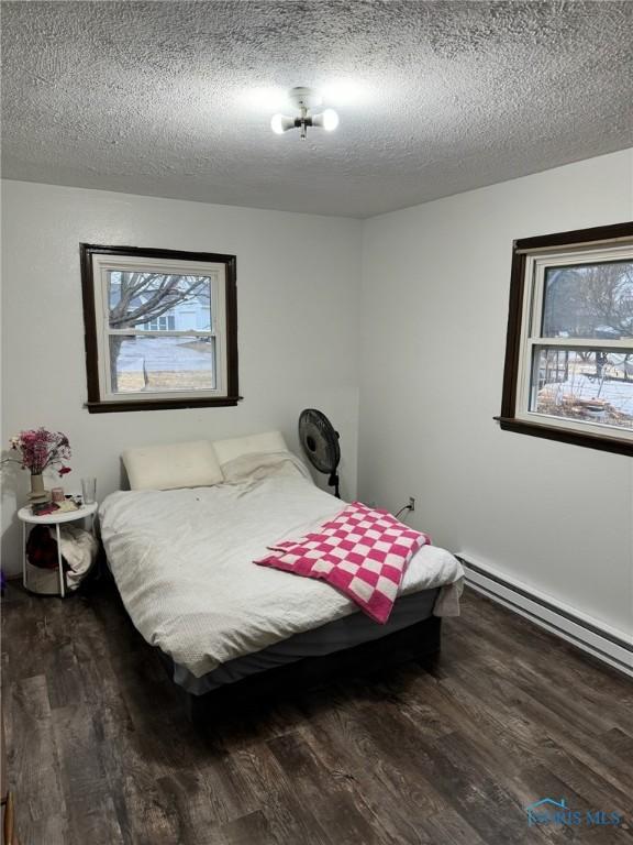 bedroom with dark wood-style floors, multiple windows, and a textured ceiling