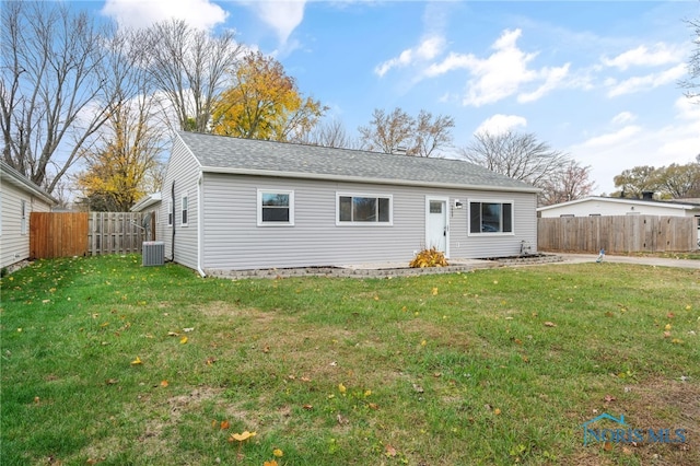 rear view of house featuring a shingled roof, a fenced backyard, a lawn, and central AC unit