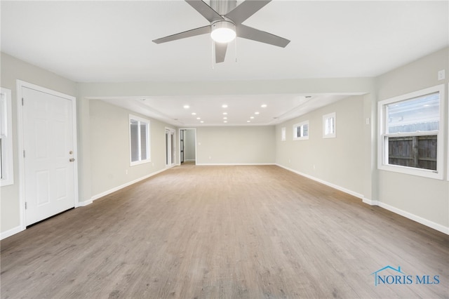 unfurnished living room with a ceiling fan, recessed lighting, light wood-style flooring, and baseboards