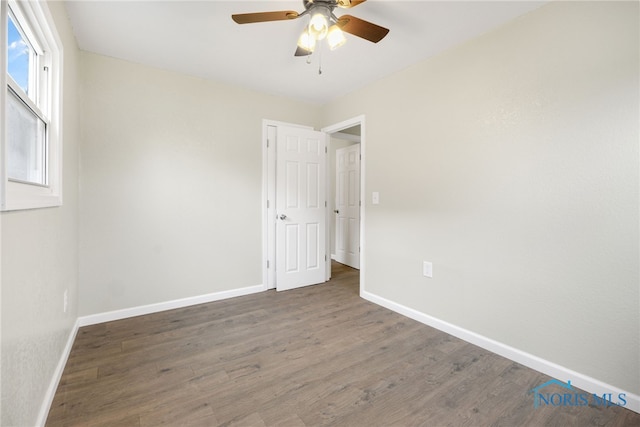 spare room with ceiling fan, dark wood-type flooring, and baseboards