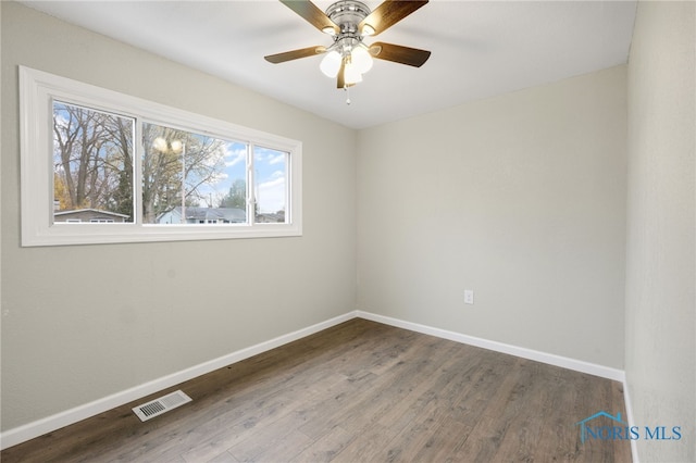 unfurnished room featuring baseboards, visible vents, and wood finished floors