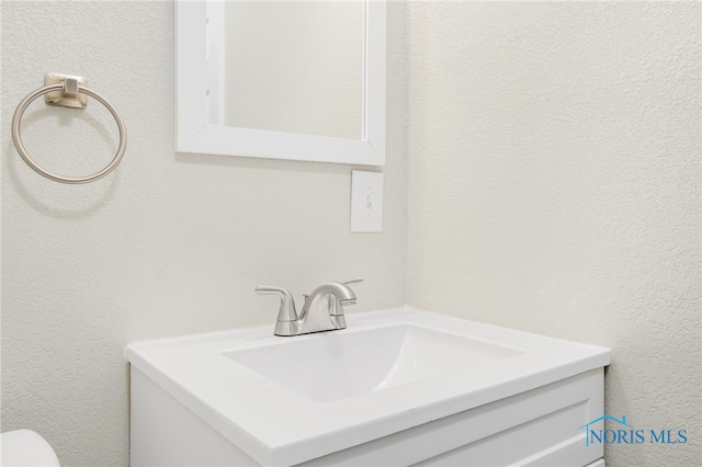 bathroom with a textured wall and vanity